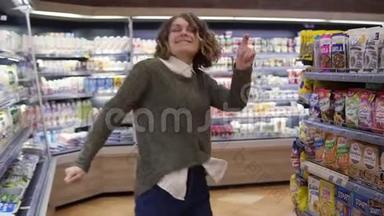 站在杂货店过道上穿着衬衫卷发跳舞的年轻女子的肖像。 兴奋的女人玩得开心，跳舞